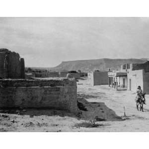   streets and adobe houses, and a boy riding a burro. A